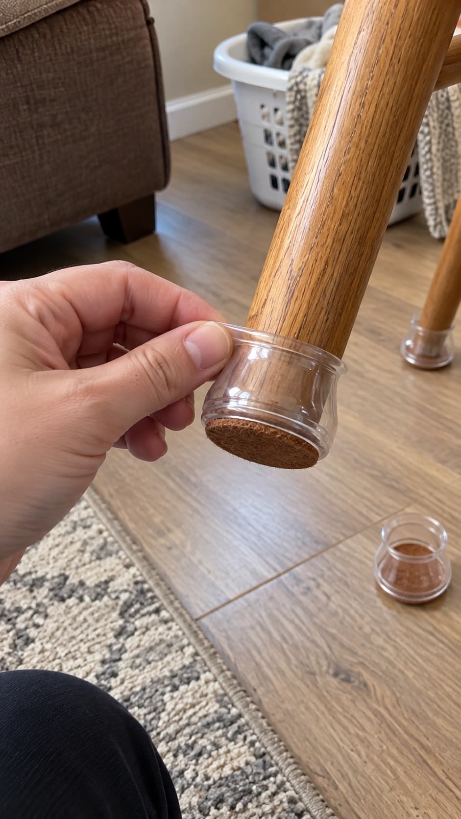 Handheld view of an adult fitting a clear cover onto a wood chair leg.