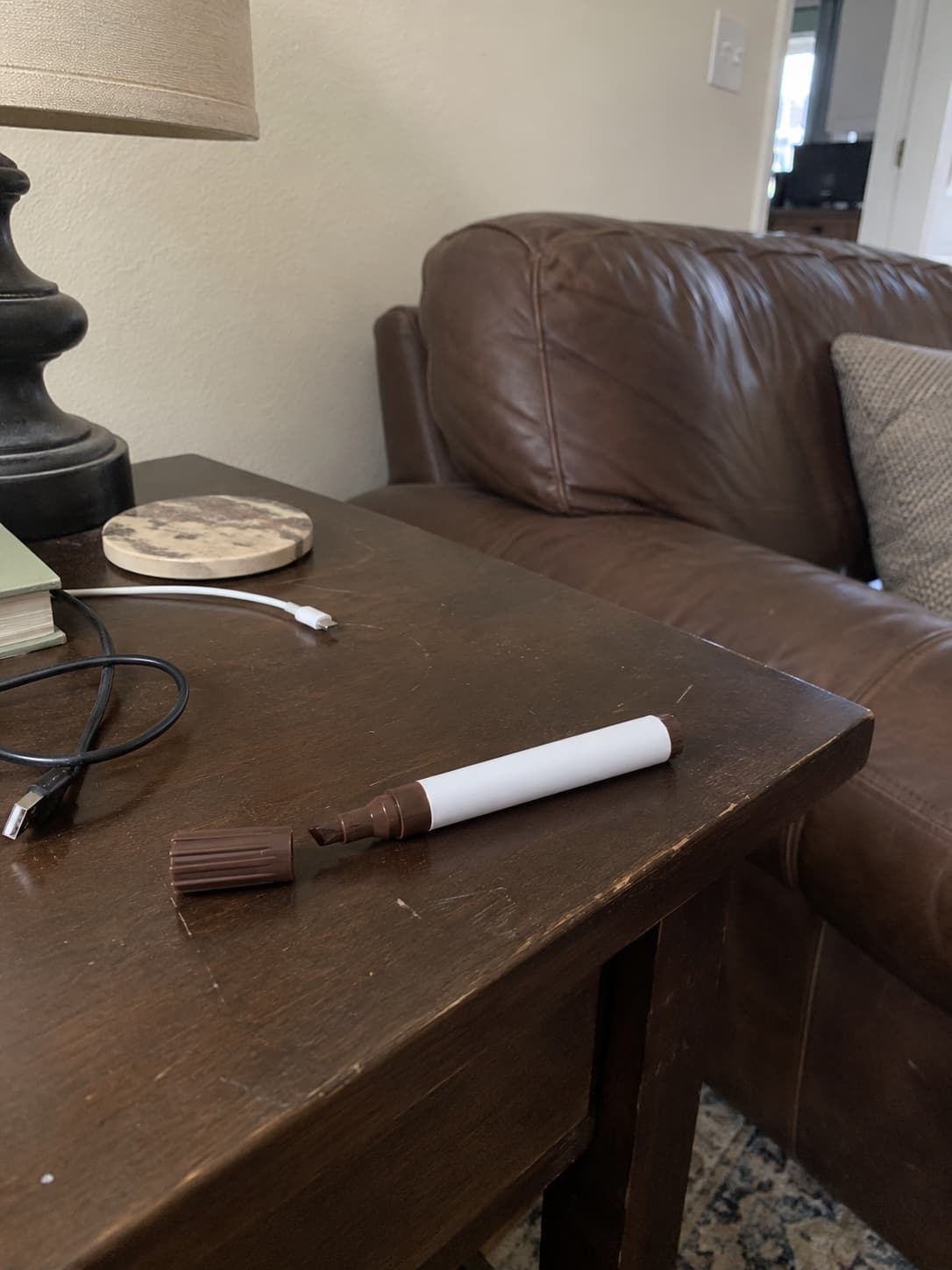 Dark brown touch-up marker beside fine scuffs on a walnut side table.